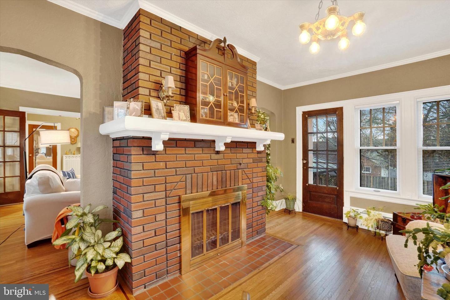 Double-sided brick fireplace at 185 Peyton Road with original built-in wood cabinet and period light fixture