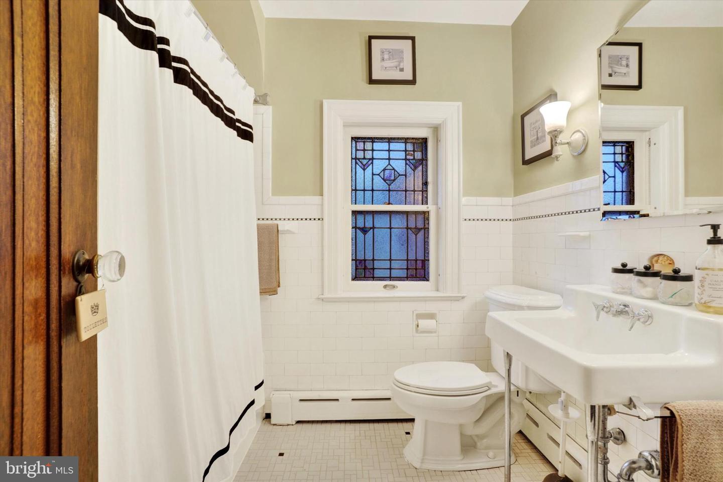 Second-floor bathroom at 185 Peyton Road with original stained glass window, white subway tile, and pedestal sink