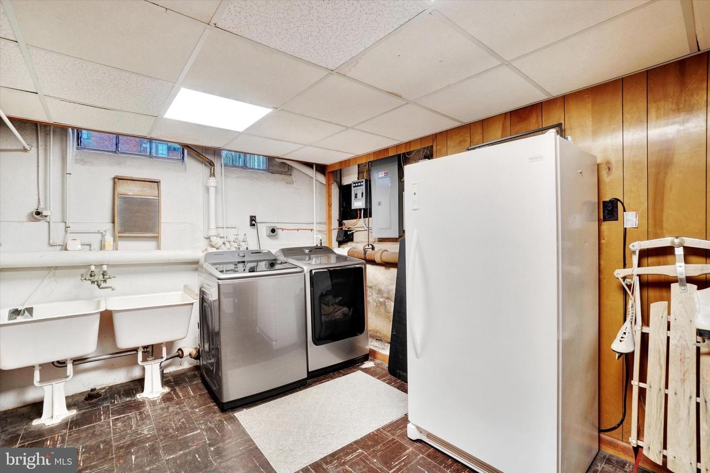 Basement laundry area at 185 Peyton Road with washer, dryer, original utility sink, and storage